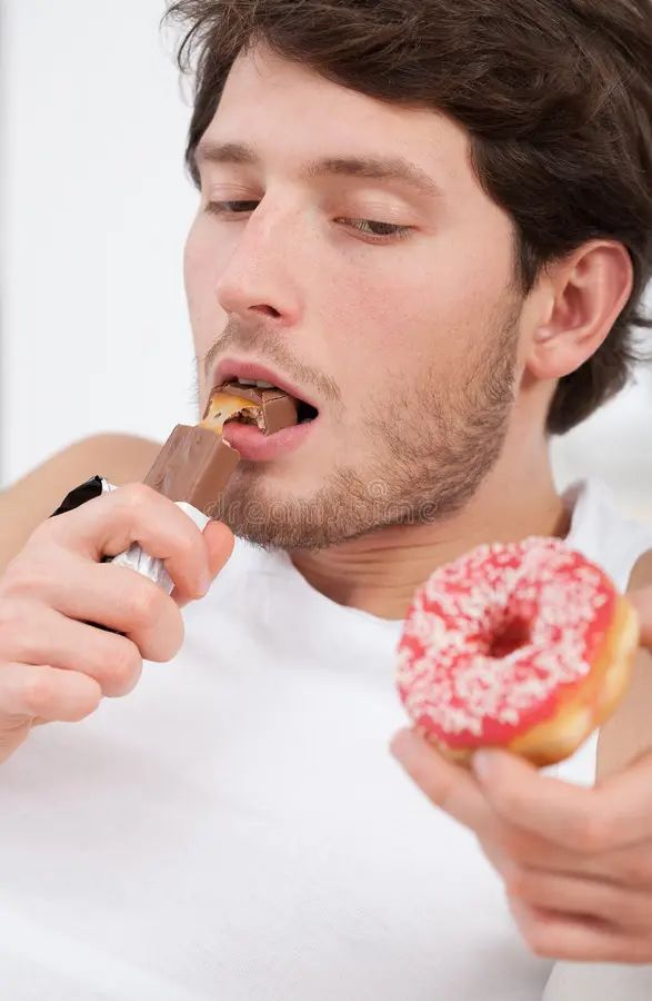 a man eating a snickers and a donut