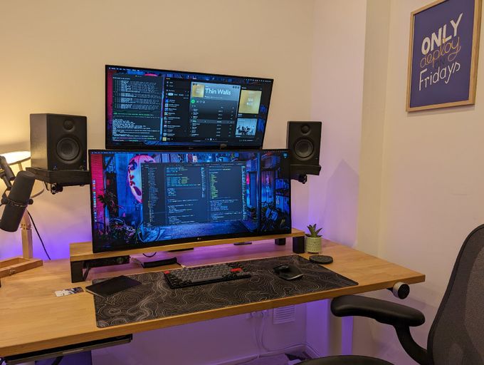the desk in my home office with the "Only deploy on Fridays" poster hanging on the right side of it